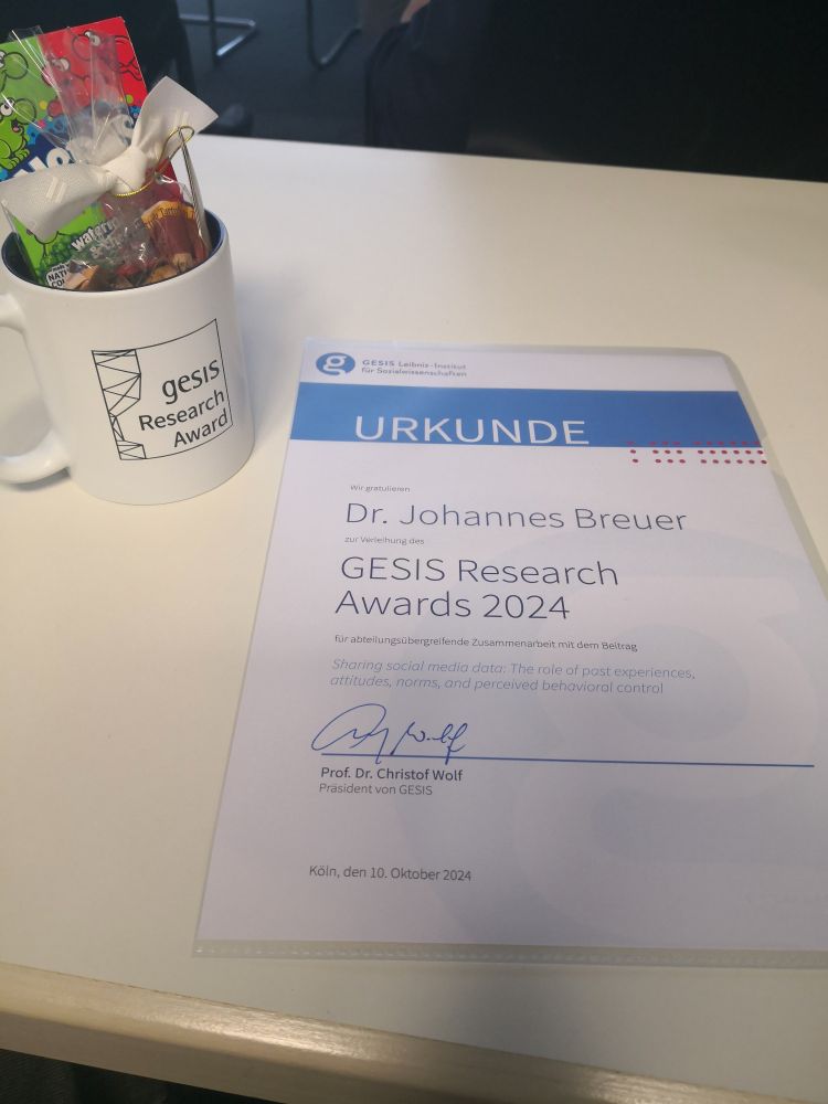 Photo of a certificate for the GESIS Research Award 2024 for the best cross-departmental collaboration and a mug with a GESIS Research Award print filled with sweets