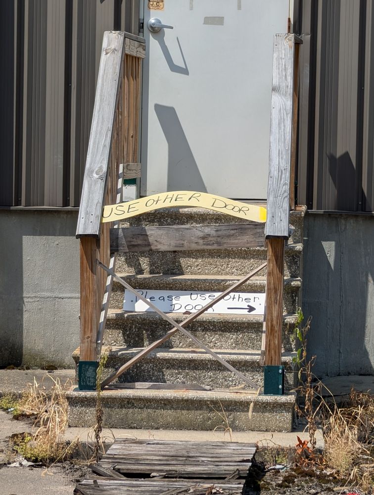 A loading dock door blocked with multiple signs saying to use the OTHER door lol