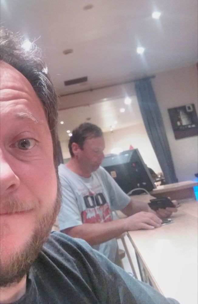 Me taking a smiling selfie as an excuse to get a picture of the man behind me at the bar, despondently counting out beer money.