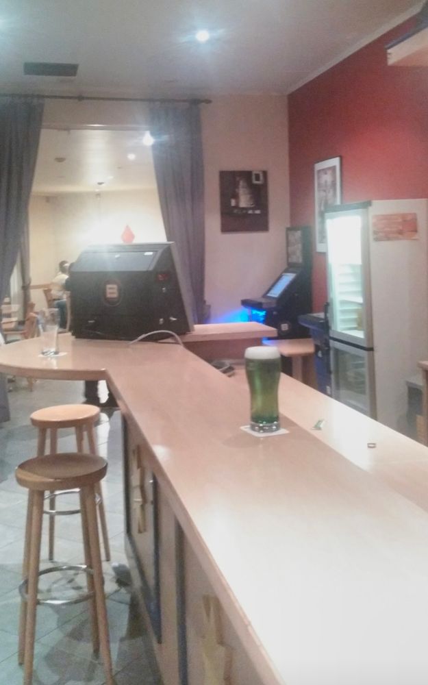 A pint glass of a mysterious green drink stands alone on a bar of pale, office furniture wood. I never found out what this was, it looked like washing up liquid. When I asked the lady behind the bar, she just said "You probably wouldn't like it"