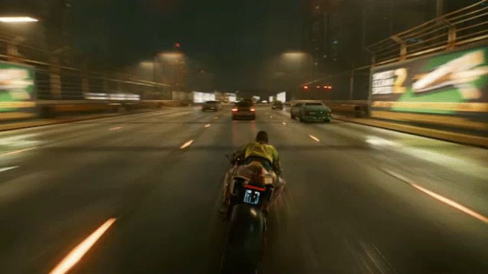 a man in a yellow shirt is riding a motorcycle down a highway at night