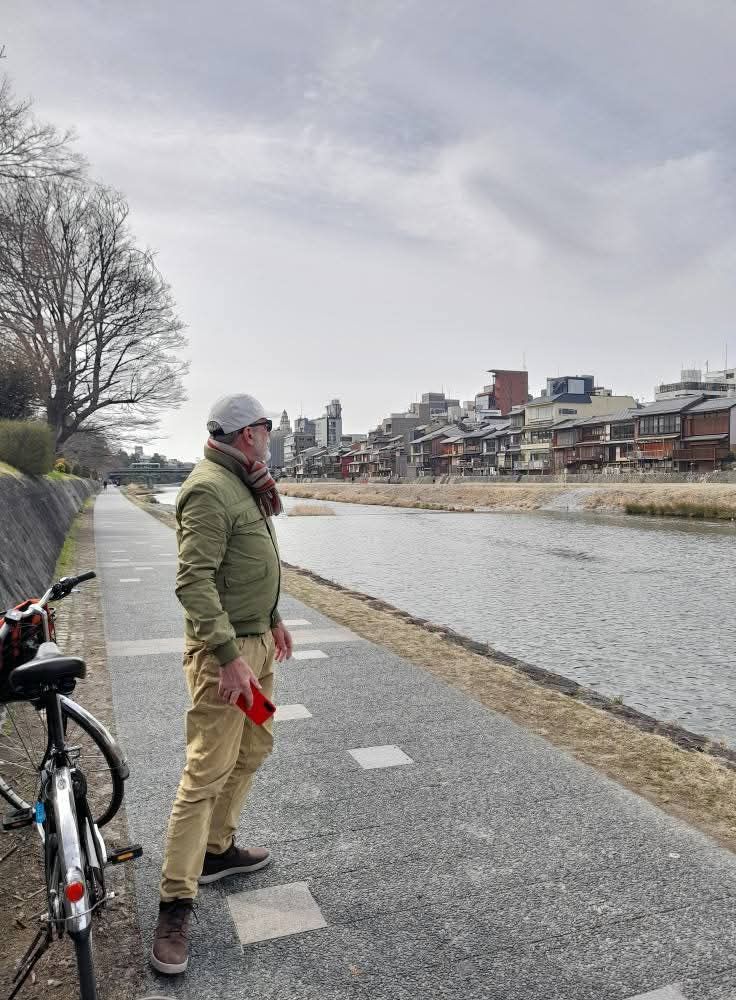 I'm standing beside a river in Kyoto, admiring the view of restaurants and houses, next to an ebike.