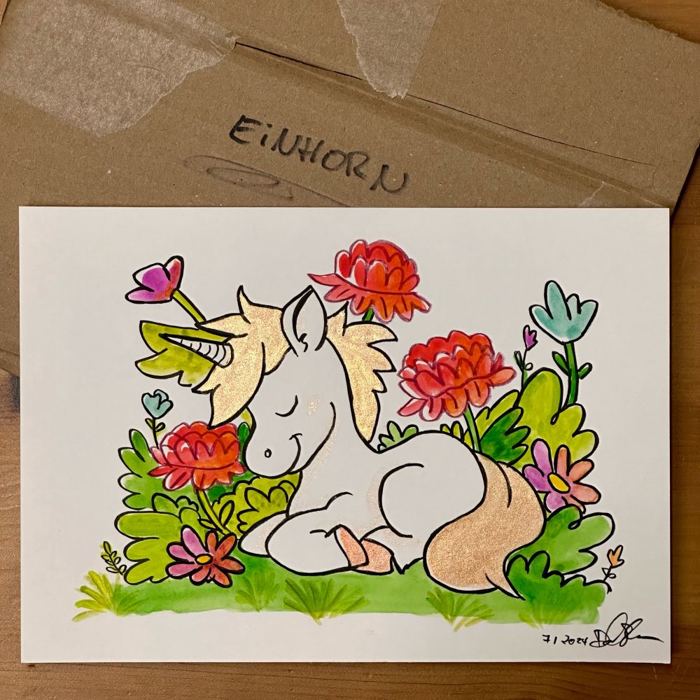 Ein handgemaltes Bild eines Einhorns inmitten einer bunten Blumenwiese. Das Einhorn hat goldene Mähne und Schwanz
