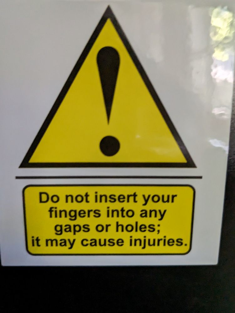 Warning sign saying "Do not insert your fingers into any gaps or holes; it may cause injuries"