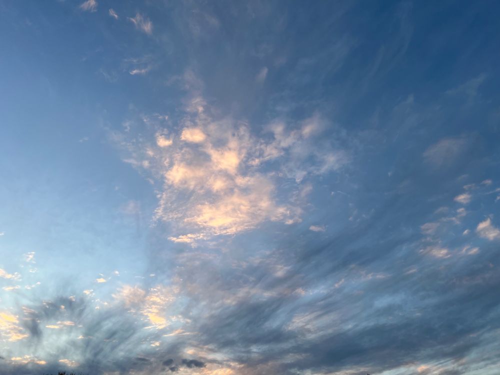 very dramatic clouds in a blue sky. one of the cloud clusters resembles a heart shape