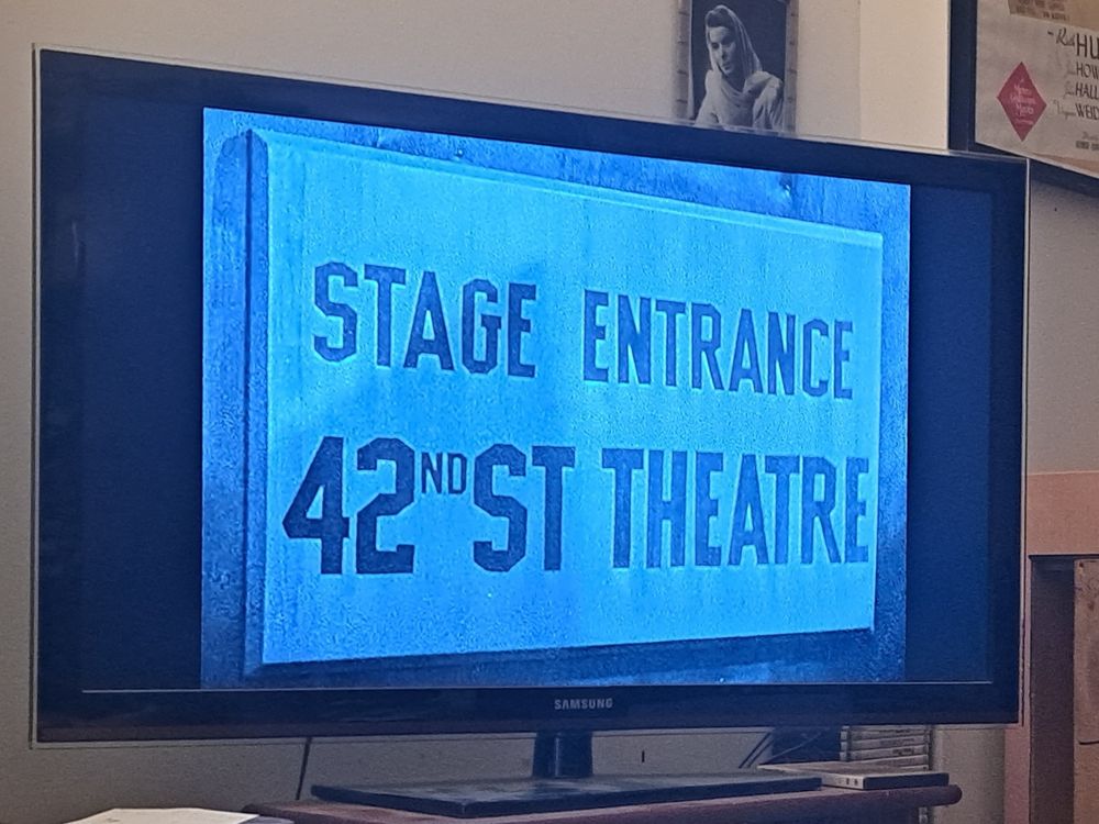 Screenshot from the movie 42nd Street. Picture is of a sign that reads "Stage Entrance 42nd Street Theatre"