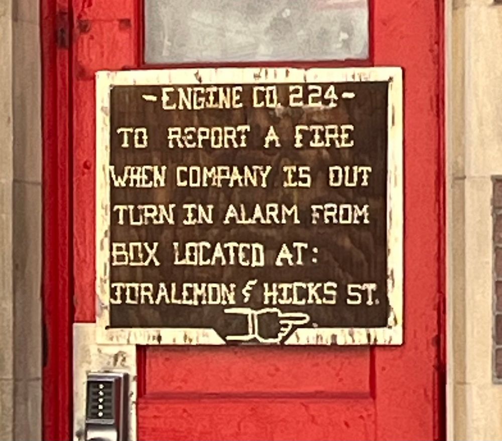 A helpful sign outside a fire station instructing anyone who came to report a fire to use an alarm on the side of the building if no one is in to field their inquiry in person