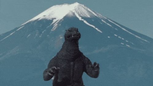 GIF of Godzilla screaming in front of a snow-covered mountain. 