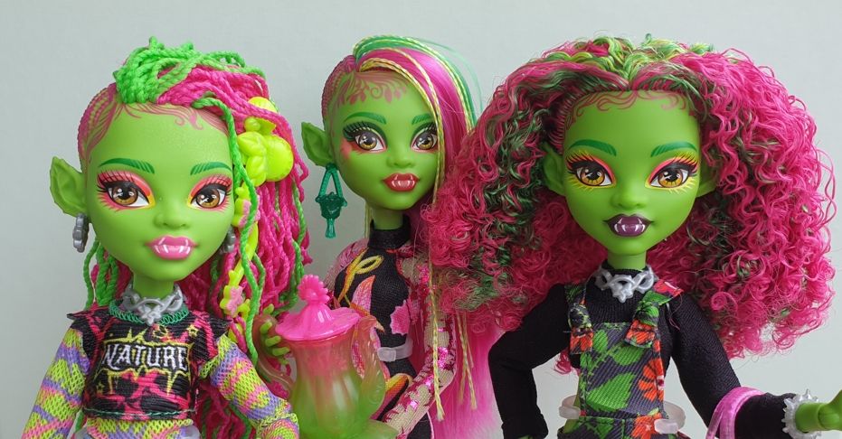 Doll photo. Monster High Core Venus, Garden Mysteries Venus, and Fearbook Venus posed together from the waist up. Core Venus wears her default ripped t-shirt over a green purple and pink mesh top, and Garden Mysteries Venus wears her black floral dress over a pink mesh top.