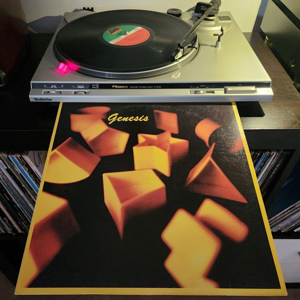 Image depicts the spinning of the 1983 Genesis vinyl album "Genesis" on a turntable along with the cover of the album.