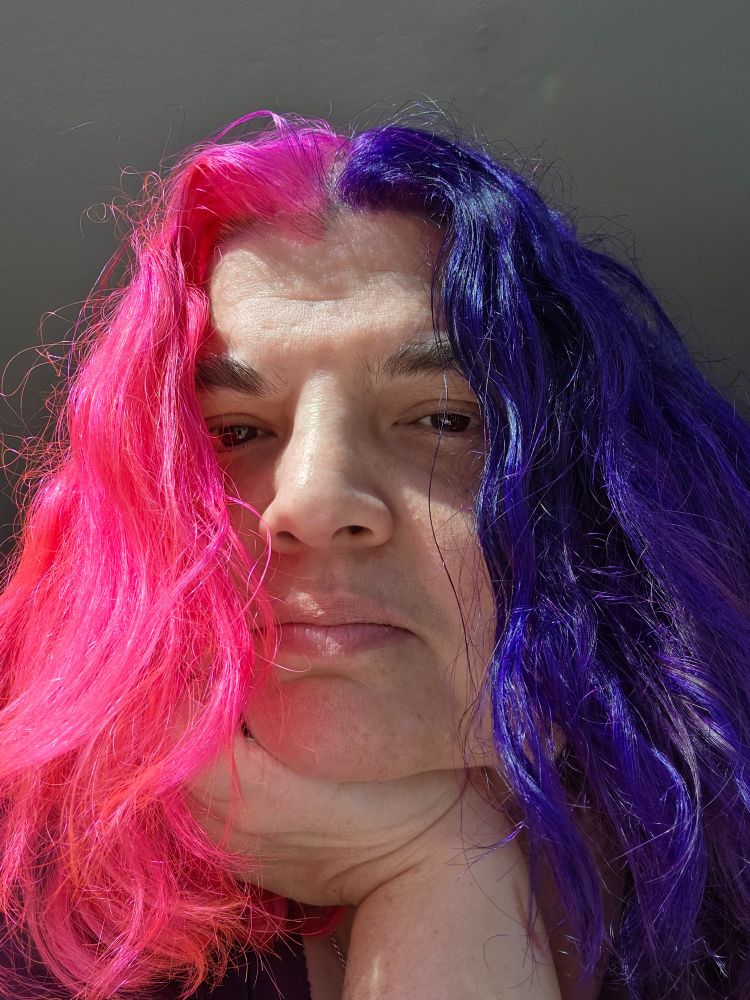 a close-up selfie of Brynna, with half her hair purple & half pink