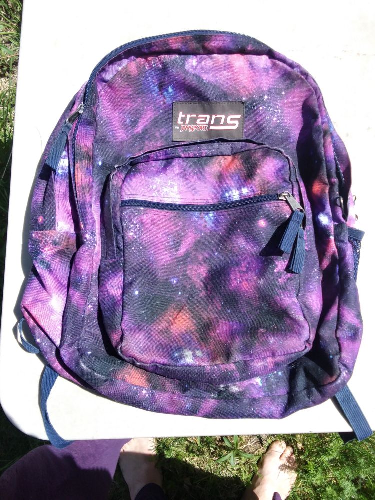 A Jansports "Trans" backpack in Gender Fluid colors arranged in a starfield or nebula design.