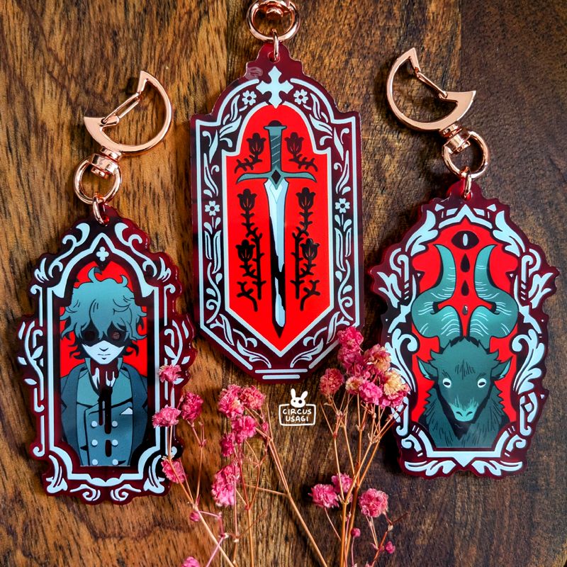 Three designs of blood red acrylic charms: a haunted man with blood dripping from the neck, a blood-stained sword, and a black ram