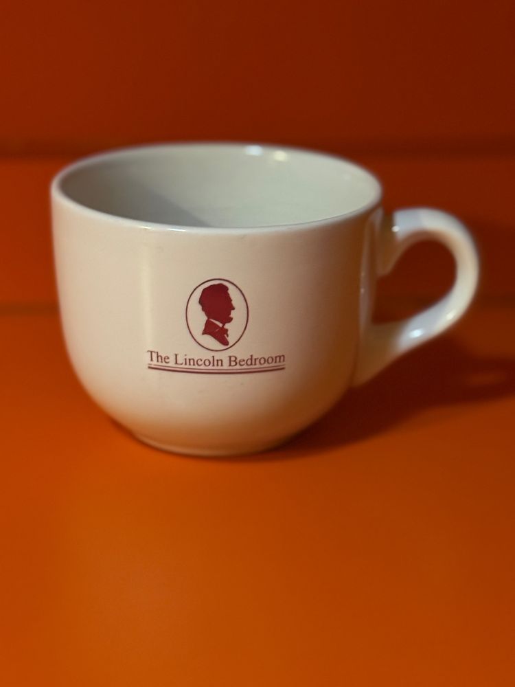 A coffee mug that says The Lincoln Bedroom against the backdrop of an orange formica kitchen counter 
