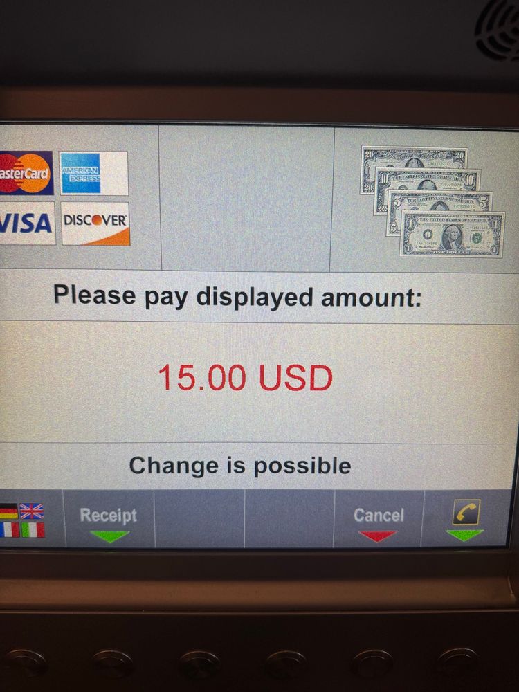 The display screen on a machine that dispenses parking tickets. It says please pay displayed amount: $15, and below that it says change is possible.