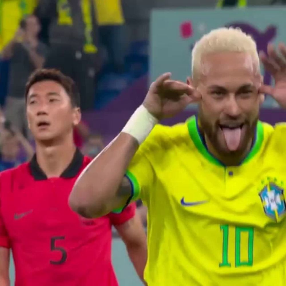 a soccer player is sticking his tongue out while another player looks on .