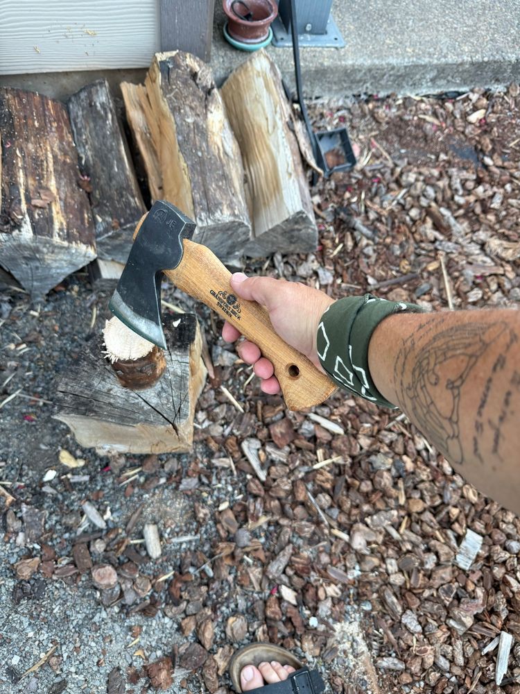 Shows someone splitting a small round of wood with a hand axe. 