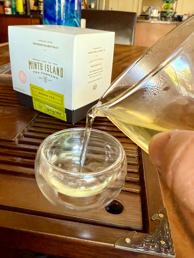 Shows someone pouring green tea from a sharing pitcher into a tea cup. 