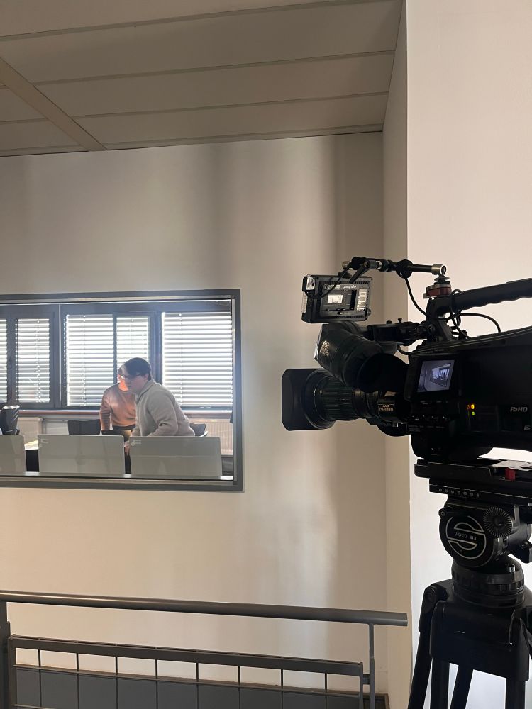 Camera pointing through a window at members of the INDI research project 