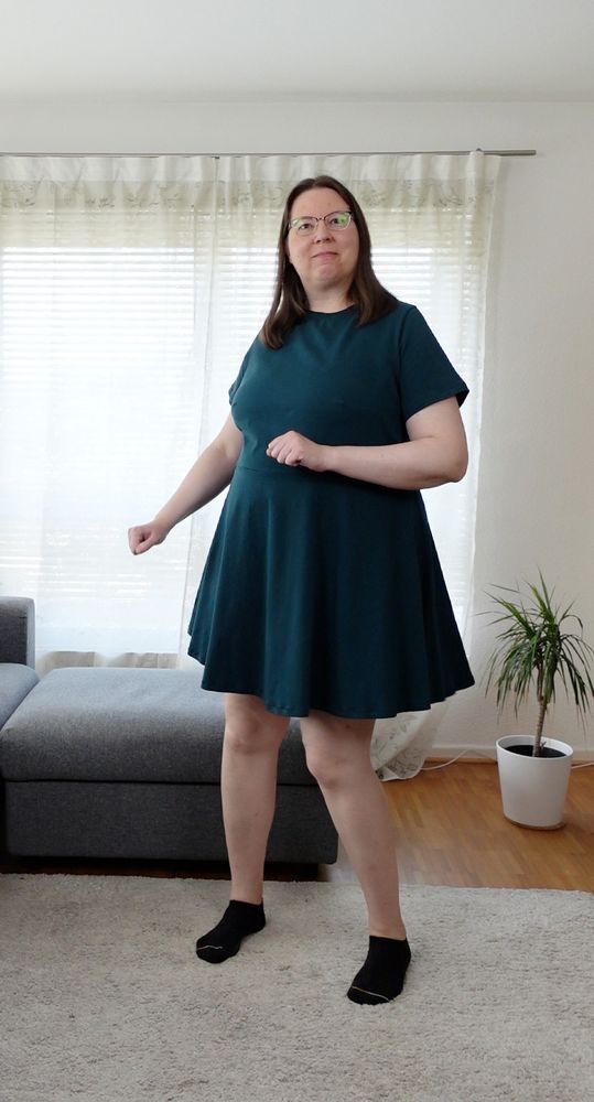 Woman in a short petrol knit dress with half circle skirt, trying to dance :D