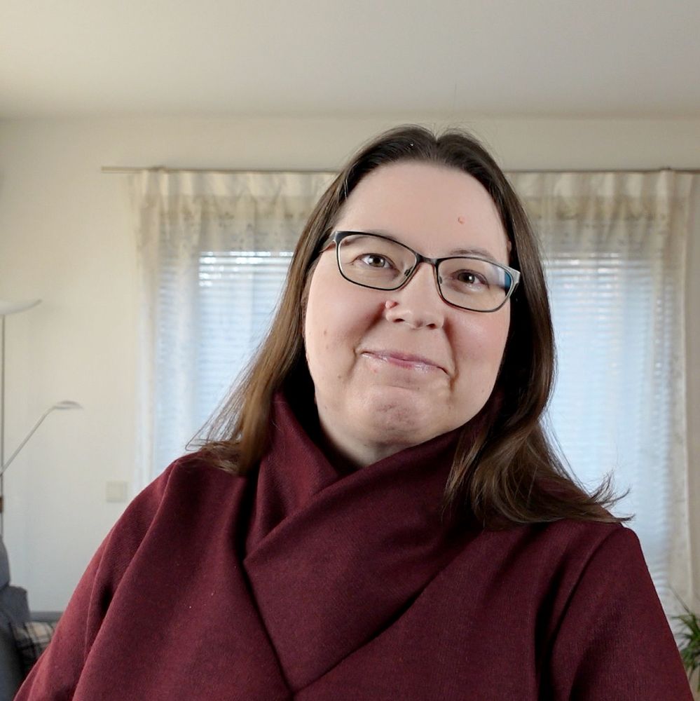 A woman in a red sweater with large shawl collar smiling into the camera.