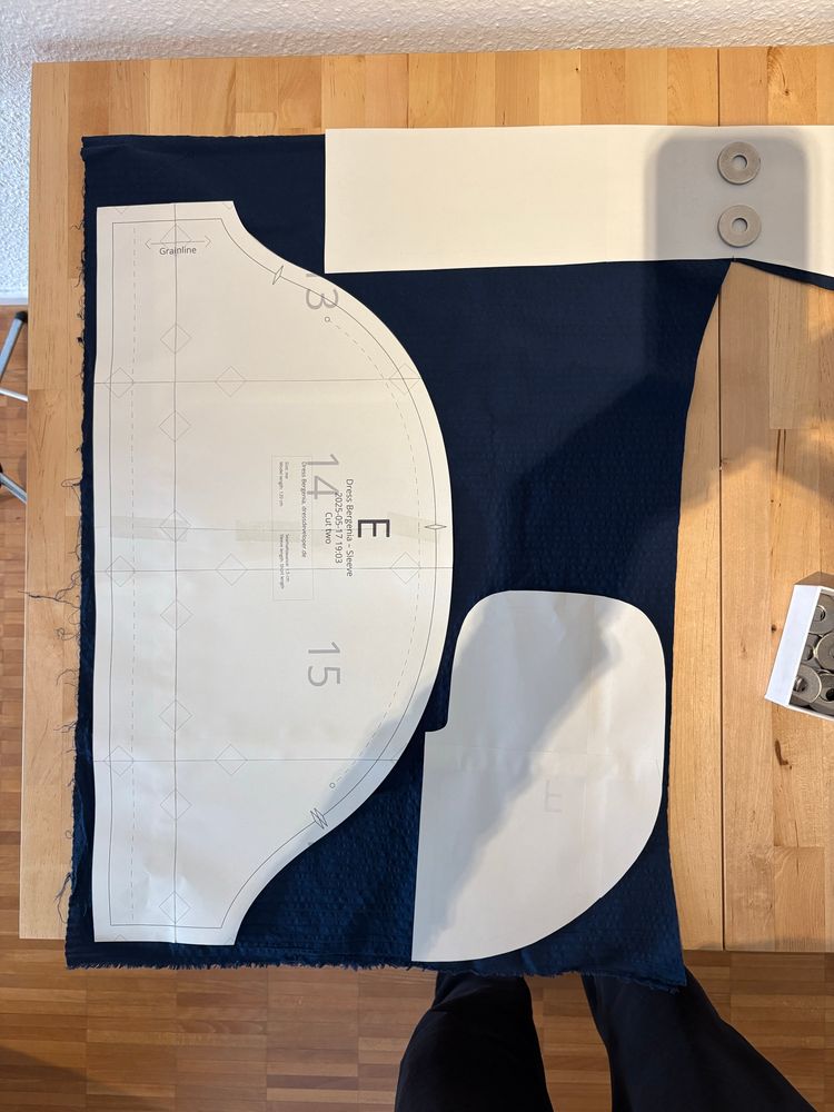 Pattern pieces ( sleeve, pocket, part of princess line panel) on deep blue fabric
