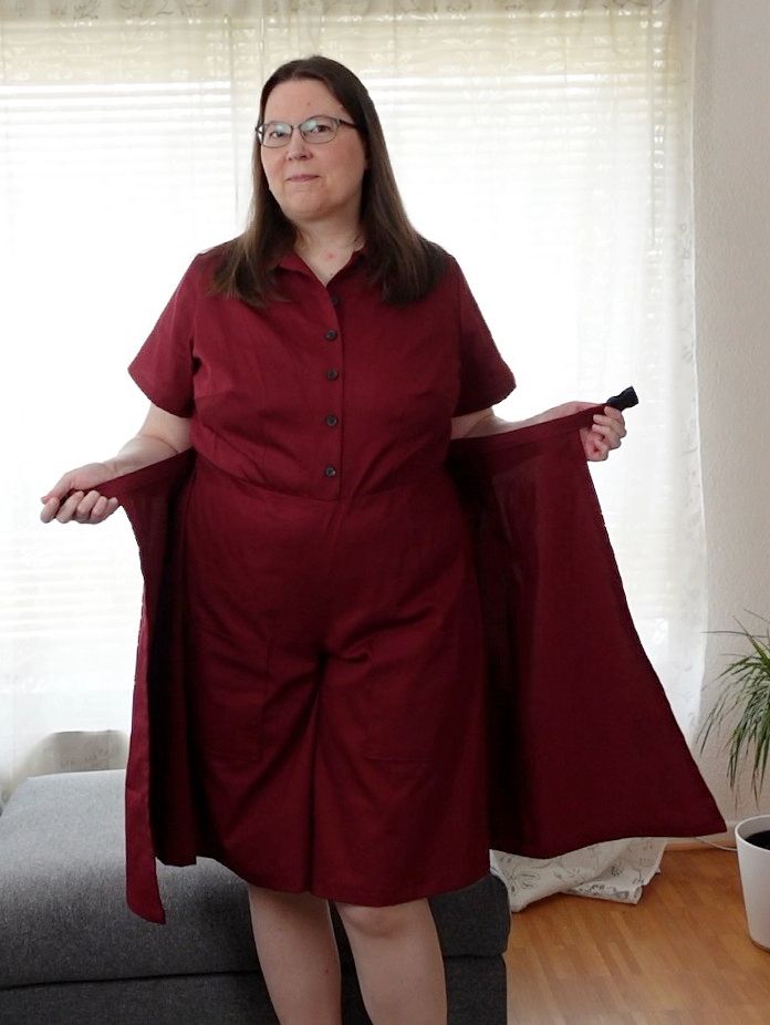 Woman in a red jumpsuit, opening the belt to show the wrapped back part