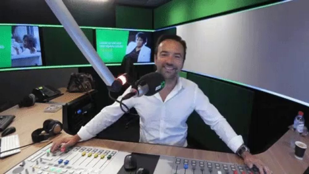 a man in a white shirt stands in front of a microphone in a studio