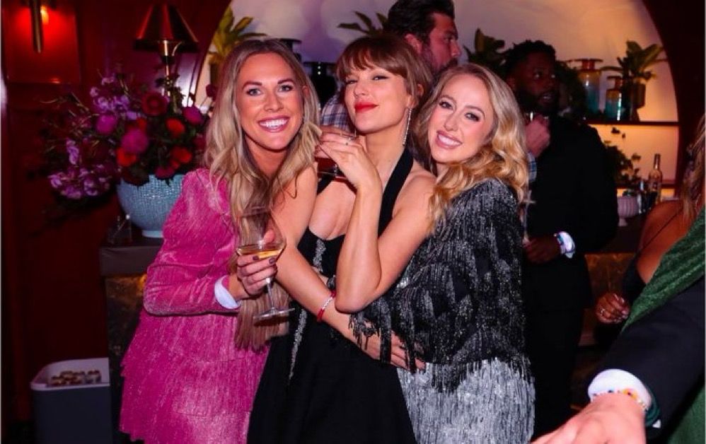 taylor swift with 2 other women. she is dressed in a black dress and is holding a red drink 