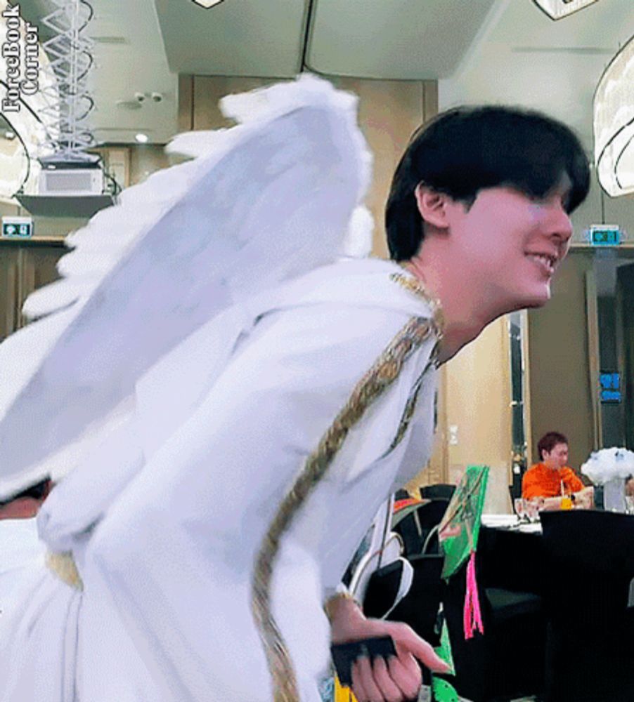 a man in a white angel costume is smiling in a room