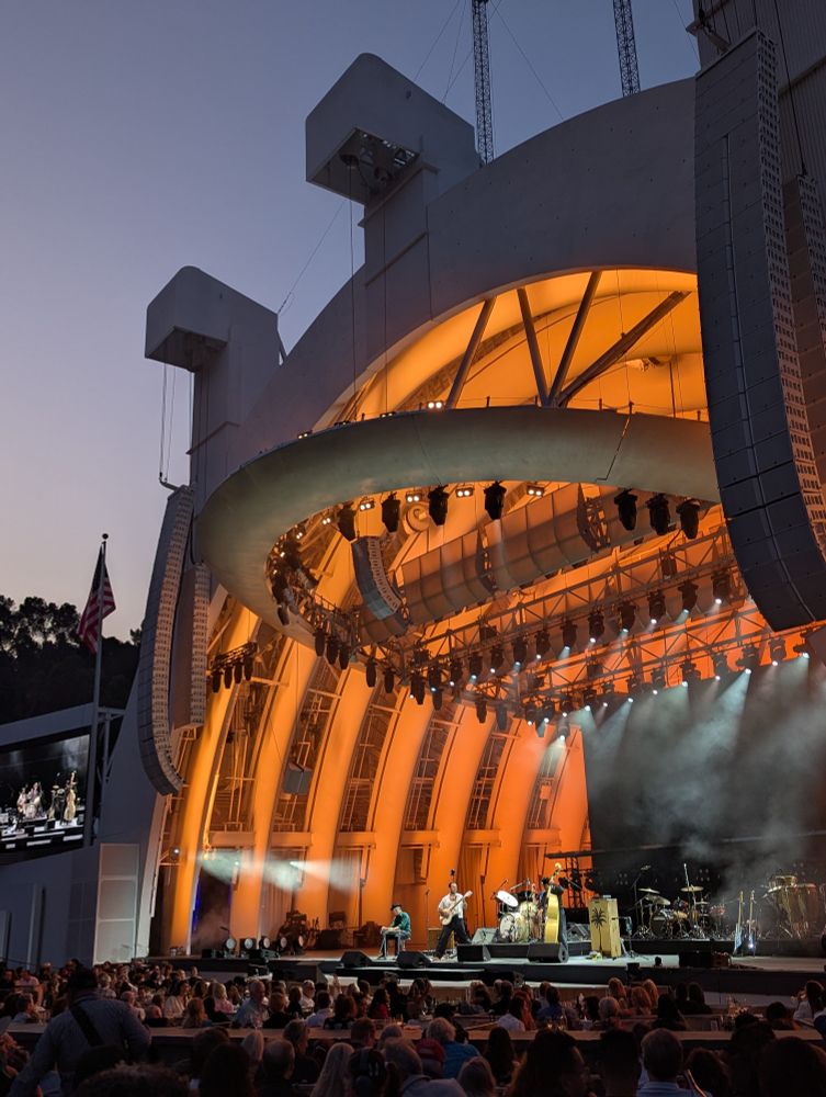 The band LA LOM on stage at the Hollywood Bowl. The stage is lit with orange light 