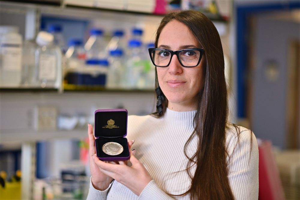 Professor Lilach Sheiner pictured in the lab holding the C.A. Wright medal in an open presentation case.