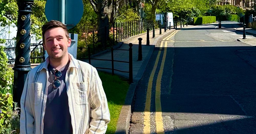 Dr Liam Rooney stood outdoors, down the hill from the Sir Gilbert Scott Building.