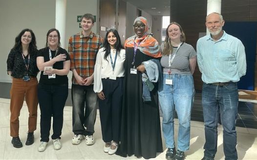 A group of staff and prize-winning students stood in a line, facing the camera, at the PGR Poster Day.