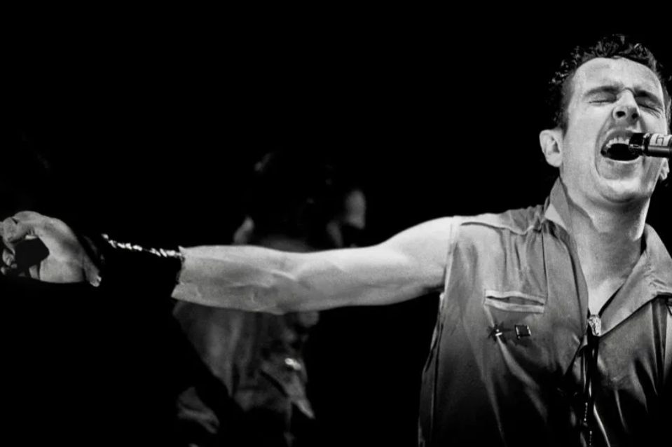 Man in sleeveless shirt singing into microphone 