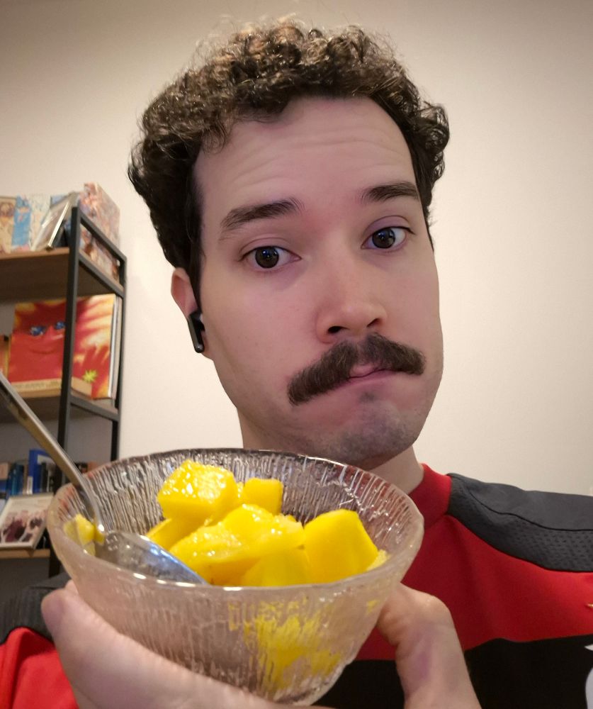 Homem bonito de bigode vestindo camisa do flamengo segura uma tigela de manga