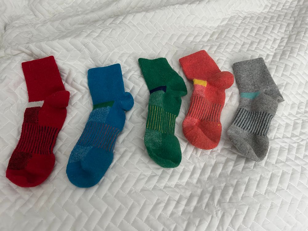 Five clean unmatched socks of the same style in five different colors 