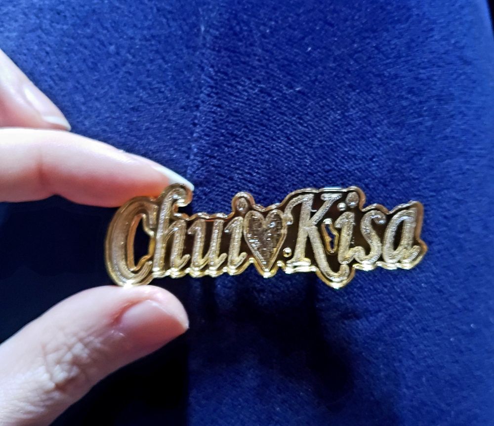 Custom engraved metallic gold acrylic pin that reads 'Chui♡Kisa', a reference to Tanakamigi Chui and Tachibana Kisa from the game Jack Jeanne 