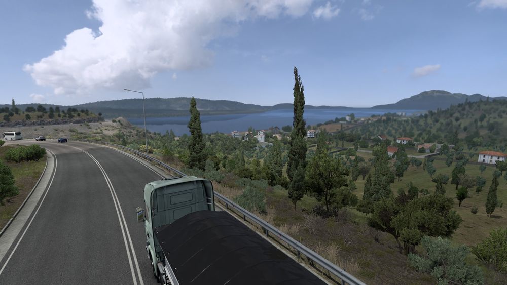 A screenshot from Euro Truck Simulator 2, featuring a long-distance look at the sea below, surrounded by green hills.