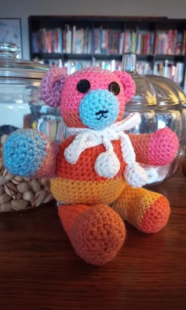 A small, multi-coloured crochet bear.