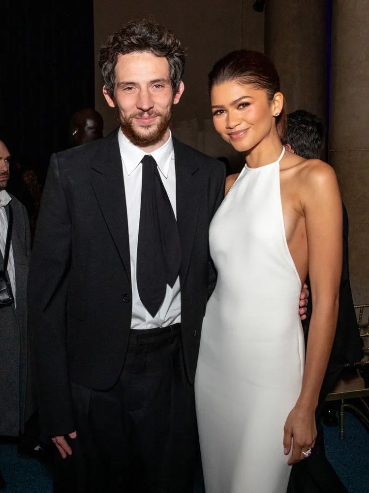 Josh O’Connor in a suit with oversized sleeves, standing with Zendaya in an elegant white floor-length gown, at the Gotham Awards 2024. 
