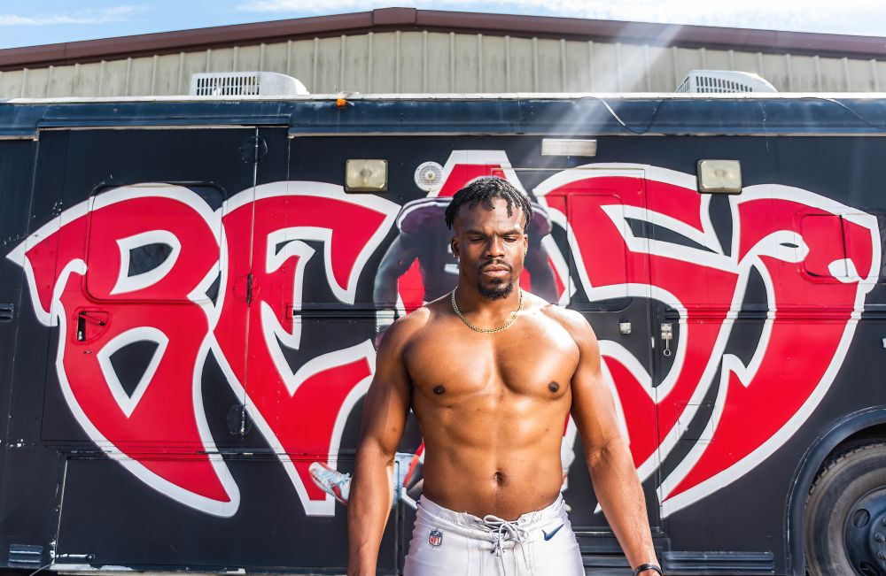 Trey Williams III posing in front of a bus.