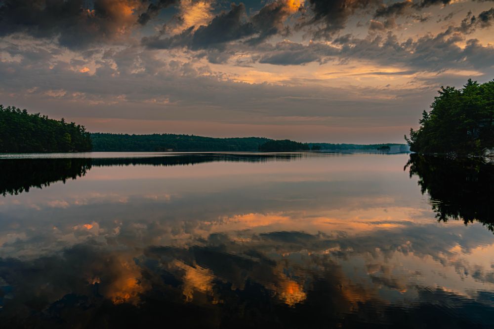 A calm lake at sunrise reflecting clouds