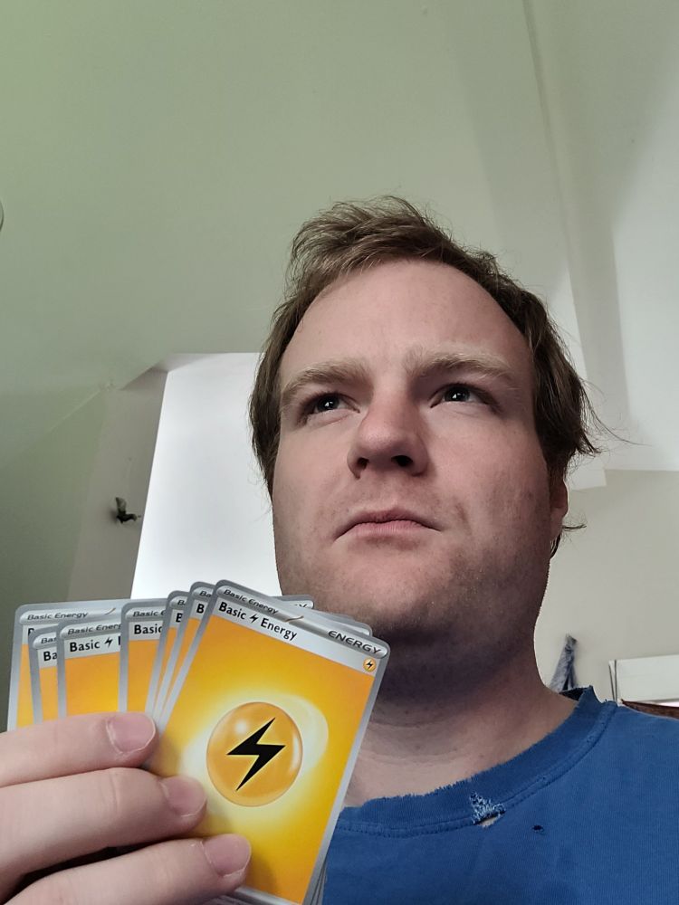 Man holds Pokémon energy cards, thinking.