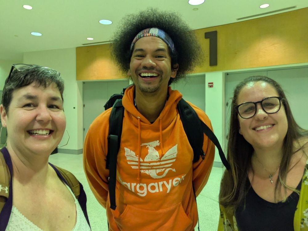 Three people smiling in an indoor setting.