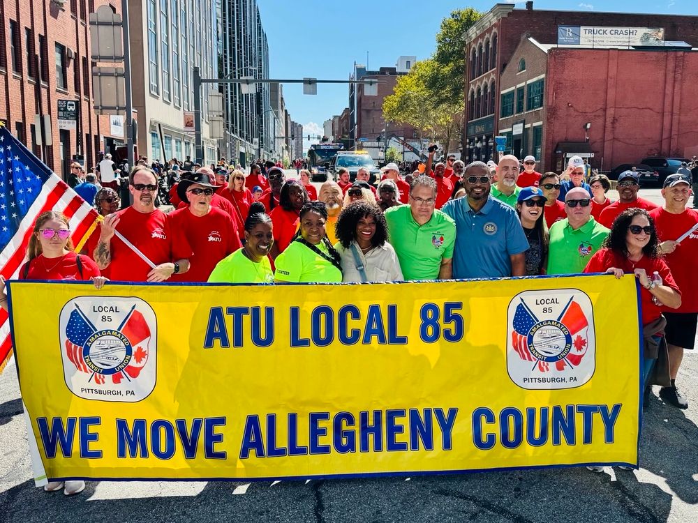 Rep. Lee marches with a group behind a yellow ATU local 85 banner. 