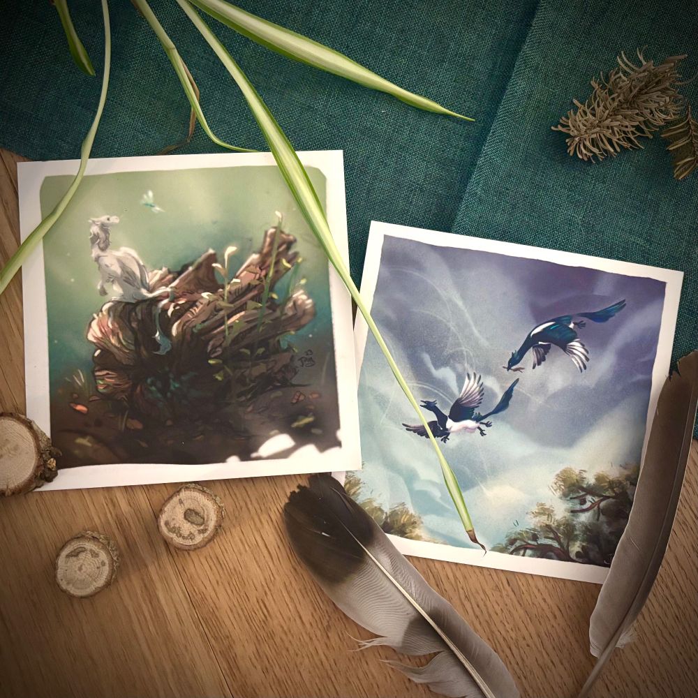 Photo of two square prints, depicting a little dragon creature on a log, and two magpie griffins