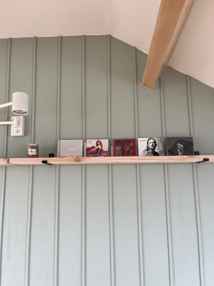 A shelf on a wall with 5 CDs on display: I Like It When You Sleep By The 1975, Speak Now, Red, Reputation, TTPD