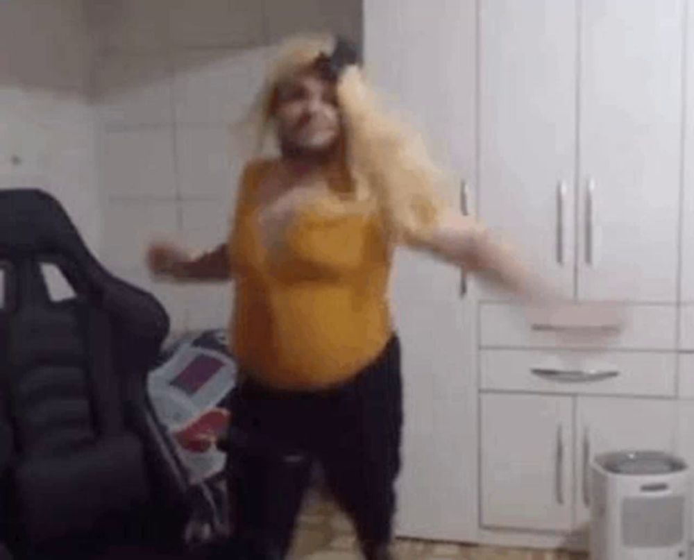 a woman in a yellow top is dancing in a room with a chair .