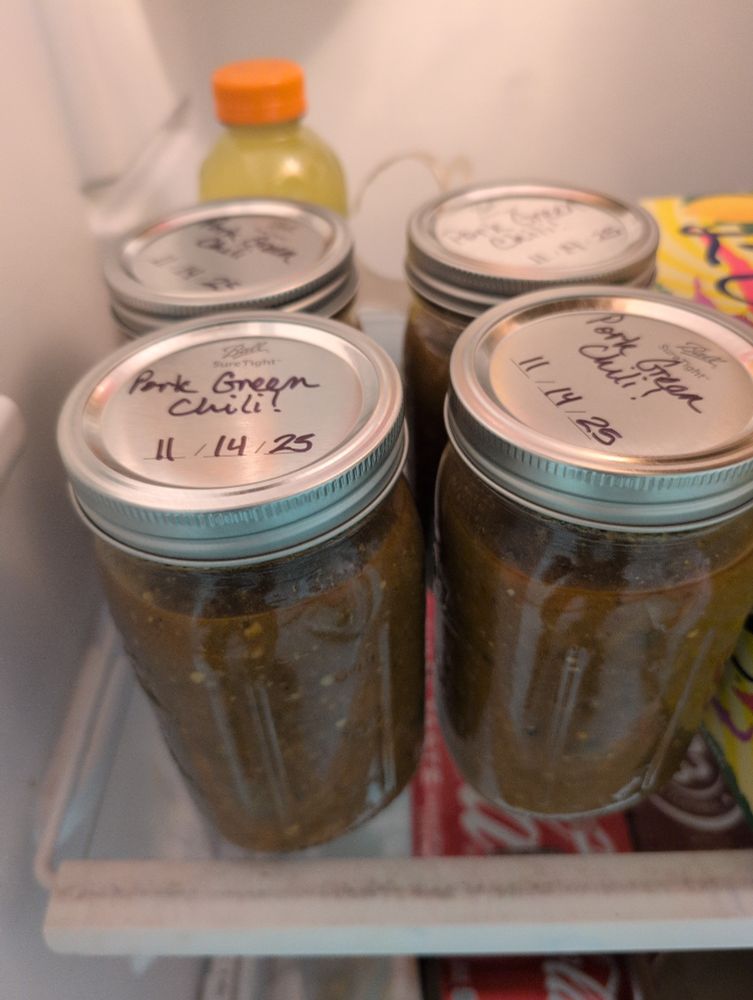 Four (4) mason jars full of green chili with "Pork Green Chili 11/14/25" written on the lids 